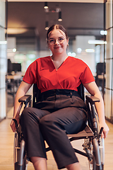 Image showing A modern young businesswoman in a wheelchair is surrounded by an inclusive workspace with glass-walled offices, embodying determination and innovation in the business world