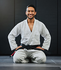 Image showing Mma, karate and training with a young man kneeling in a gym, health studio or dojo in his gi or uniform. Portrait of a male training, exercising and learning self defense in a workout and fight class