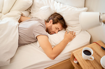 Image showing Sleeping, resting and sleepy man lying in bed with his eyes closed in a deep sleep in his bedroom. Rest, relax and tired person at home dreaming and relaxing at his house taking a late morning nap