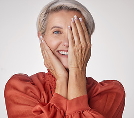 Image showing Eye, half and smile of a senior woman isolated against a grey background in a studio. Portrait of an elderly model lady in beauty with hands over her face in wellness, health and teeth.