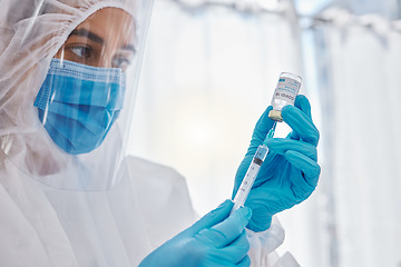 Image showing Medical scientist, doctor or healthcare worker in a safety suit ready to give the covid vaccine. Hospital employee holding, looking and working with care on a corona medicine vial at a hospital