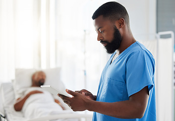 Image showing Black doctor using a digital tablet while working with sick patients at a hospital, serious and thinking. African American health care worker using online organizer or planner to keep track of task