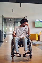 Image showing A sad businessman in a wheelchair occupies a hallway within a modern startup coworking center, embodying inclusivity and determination in the business environment