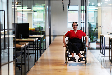 Image showing A modern young businesswoman in a wheelchair is surrounded by an inclusive workspace with glass-walled offices, embodying determination and innovation in the business world