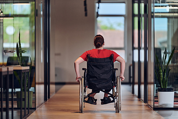 Image showing A modern young businesswoman in a wheelchair is surrounded by an inclusive workspace with glass-walled offices, embodying determination and innovation in the business world