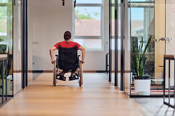 Image showing A modern young businesswoman in a wheelchair is surrounded by an inclusive workspace with glass-walled offices, embodying determination and innovation in the business world