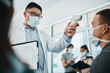 Image showing Doctor testing covid temperate in hospital appointment to prevent the spread of the virus. Healthcare compliance worker with health insurance document and face mask checking or scanning patient head