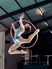 Image showing Sports woman, performance and ring in the air for gymnastics show. Fitness girl doing artistic pose and stretch for acrobat stunt. Young and beautiful athlete in gym with hula hoop and flexible body.