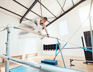 Image showing Gymnastics, man and sports with a gymnast swinging on a horizontal bar inside of a gym for fitness, training and workout. Sport, exercise and practice with an athlete holding onto parallel bars