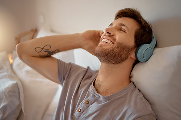 Image showing Man listening to music, podcast or radio with headphones at home while relaxing, smile and happy in his bedroom. Peaceful, freedom and young male streaming an online audio playlist enjoying weekend