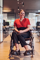 Image showing A modern young businesswoman in a wheelchair is surrounded by an inclusive workspace with glass-walled offices, embodying determination and innovation in the business world