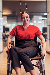 Image showing A modern young businesswoman in a wheelchair is surrounded by an inclusive workspace with glass-walled offices, embodying determination and innovation in the business world