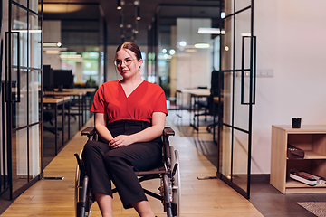 Image showing A modern young businesswoman in a wheelchair is surrounded by an inclusive workspace with glass-walled offices, embodying determination and innovation in the business world