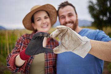 Image showing Farmer or gardener couple showing love heart sign with their hands outdoors on an organic or sustainable farm. Happy and excited activists support sustainability or organic farming