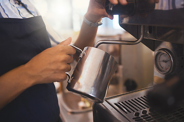 Image showing Coffee shop, barista and waitress working in a cafe and pouring a fresh drink in a restaurant while in an apron. Closeup of a hand foaming or steaming milk in the service and hospitality industry.