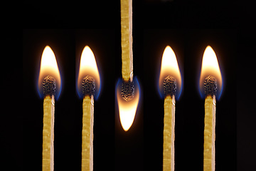 Image showing Fire and flame burning on matches sticks as light in the dark against black studio background. Closeup detail of a row of five bright art or artistic matchsticks with flames lit for heat