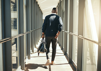 Image showing Businessman at airport walking for work travel and male african morning commute to city. Transport service from airplane terminal to hotel, rear view of modern worker carrying hand luggage bag trip.