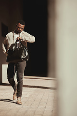 Image showing A watch, time and a business man late to a deal or meeting with a bag in the city. Busy black male worker, walking or travel or journey or rushing to a bus or plane for corporate business trip