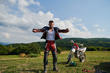 Image showing A professional motocross rider, clad in a full suit, gloves, and backpack, prepares for a daring adventure through the forest, geared up for an adrenaline-pumping off-road journey