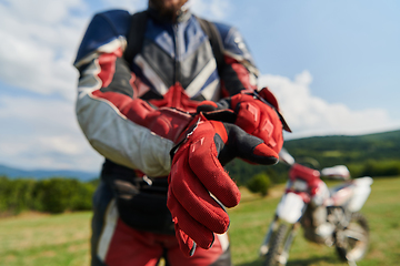 Image showing A professional motocross rider putting his gloves and preparing for a professional motocross ride