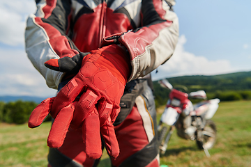 Image showing A professional motocross rider putting his gloves and preparing for a professional motocross ride