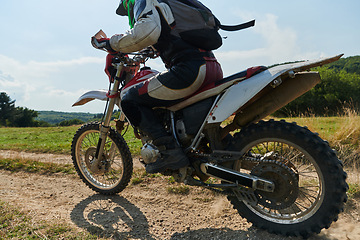 Image showing A professional motocross rider exhilaratingly riding a treacherous off-road forest trail on their motorcycle.