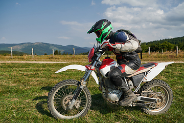 Image showing A motorcyclist equipped with professional gear, rides motocross on perilous meadows, training for an upcoming competition.