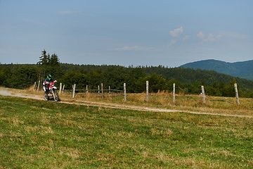 Image showing A professional motocross rider exhilaratingly riding a treacherous off-road forest trail on their motorcycle.