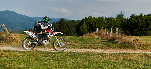 Image showing A professional motocross rider exhilaratingly riding a treacherous off-road forest trail on their motorcycle.