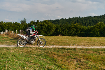 Image showing A professional motocross rider exhilaratingly riding a treacherous off-road forest trail on their motorcycle.