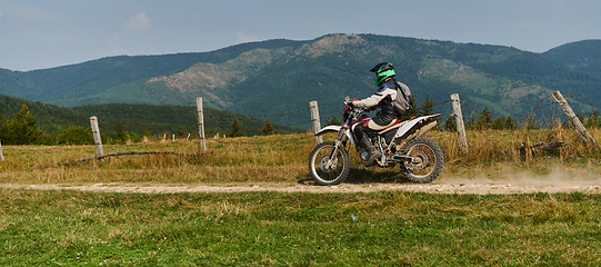 Image showing A professional motocross rider exhilaratingly riding a treacherous off-road forest trail on their motorcycle.