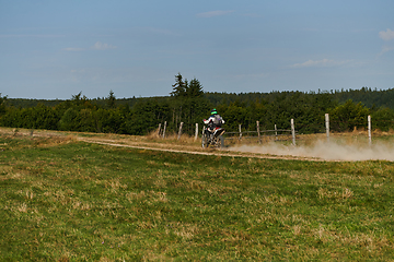 Image showing A professional motocross rider exhilaratingly riding a treacherous off-road forest trail on their motorcycle.