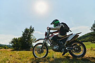 Image showing A motorcyclist equipped with professional gear, rides motocross on perilous meadows, training for an upcoming competition.