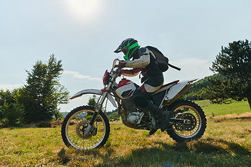 Image showing A motorcyclist equipped with professional gear, rides motocross on perilous meadows, training for an upcoming competition.