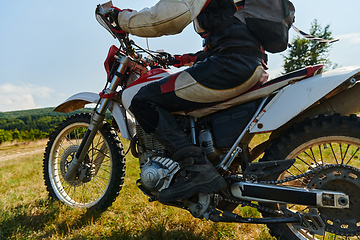 Image showing A motorcyclist equipped with professional gear, rides motocross on perilous meadows, training for an upcoming competition.