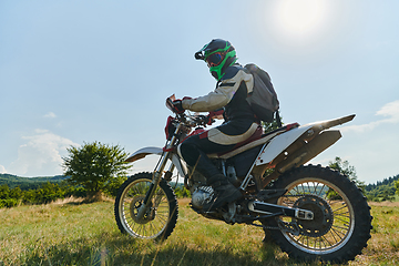 Image showing A motorcyclist equipped with professional gear, rides motocross on perilous meadows, training for an upcoming competition.