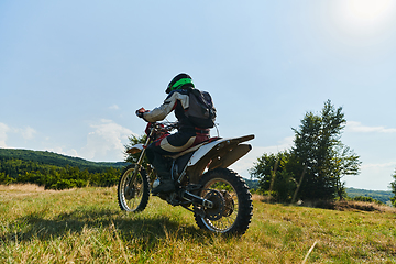 Image showing A motorcyclist equipped with professional gear, rides motocross on perilous meadows, training for an upcoming competition.