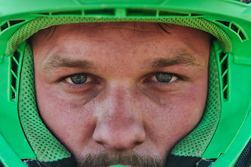 Image showing The determined face of a professional motocross rider, adorned with a protective helmet, reflects unwavering focus and readiness for an adrenaline-fueled adventure.