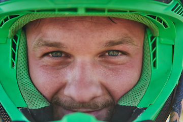 Image showing The determined face of a professional motocross rider, adorned with a protective helmet, reflects unwavering focus and readiness for an adrenaline-fueled adventure.