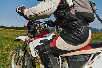 Image showing A motorcyclist equipped with professional gear, rides motocross on perilous meadows, training for an upcoming competition.