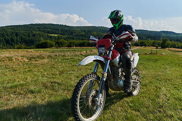 Image showing A motorcyclist equipped with professional gear, rides motocross on perilous meadows, training for an upcoming competition.