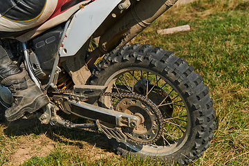 Image showing Close up photo of a professional motocross rider in action, showcasing the tire and various components of the motorcycle as they navigate the challenging off-road terrain with speed and precision.