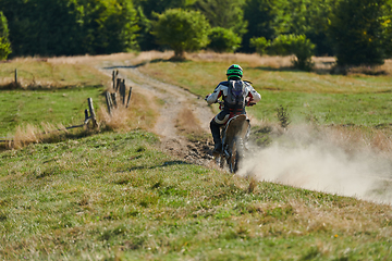 Image showing A professional motocross rider exhilaratingly riding a treacherous off-road forest trail on their motorcycle.