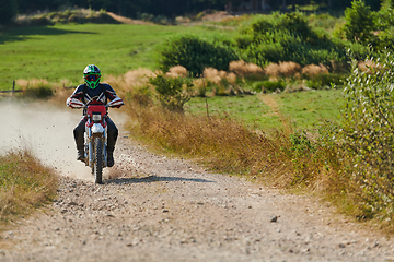 Image showing A professional motocross rider exhilaratingly riding a treacherous off-road forest trail on their motorcycle.