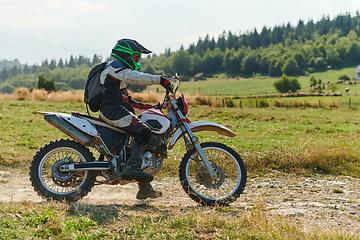 Image showing A professional motocross rider exhilaratingly riding a treacherous off-road forest trail on their motorcycle.