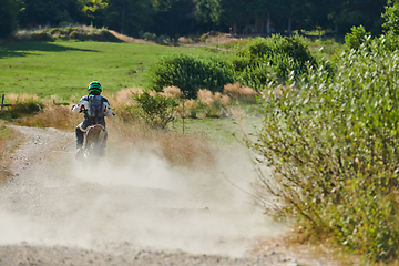 Image showing A professional motocross rider exhilaratingly riding a treacherous off-road forest trail on their motorcycle.