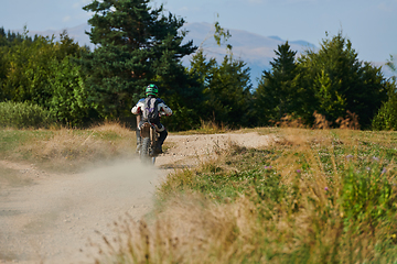 Image showing A professional motocross rider exhilaratingly riding a treacherous off-road forest trail on their motorcycle.