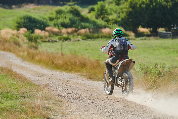 Image showing A professional motocross rider exhilaratingly riding a treacherous off-road forest trail on their motorcycle.