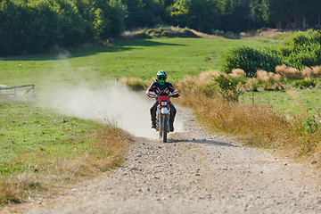 Image showing A professional motocross rider exhilaratingly riding a treacherous off-road forest trail on their motorcycle.