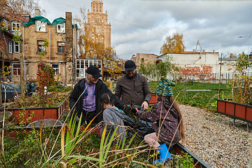 Image showing A modern family parents and children, is working together to beautify their front yard with flowers in preparation for the upcoming holiday season.